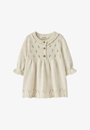 Robe pour bébé en tricot crème avec des manches longues, boutons en bois sur le devant, col volanté et motifs décoratifs en eyelets.