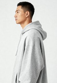 Felpa grigia oversize realizzata in tessuto morbido, con cappuccio regolabile, spalle scese e una vestibilità rilassata.