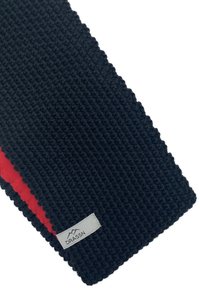 Knitted scarf in dark navy with a red stripe. Features a textured pattern and a small gray label with the brand name "DRASSN."
