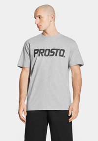 Szara bawełniana koszulka z krótkim rękawem z wyraźnym czarnym logo "PROSTO." na przodzie. Standardowy krój, prosty okrągły dekolt.