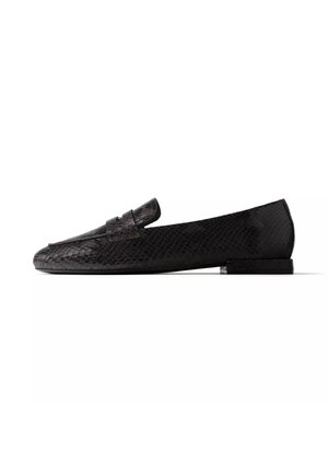Mocassin noir à petit talon avec texture peau de serpent et une bride sur le dessus, montré de profil sur fond blanc.