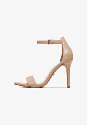 Beżowy, skórzany sandał na wysokim obcasie z cienkim paskiem wokół kostki zapinanym na złotą klamrę, otwartym noskiem i smukłym szpilkowym obcasem.