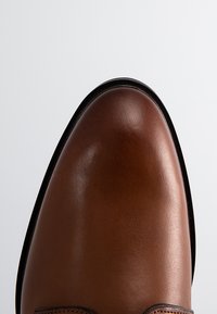 Braune Lederschuhe mit glatter Oberfläche, runder Spitze, schwarzer Sohle und minimalen stikerei Details. Klassisches Design mit einem polierten Look.