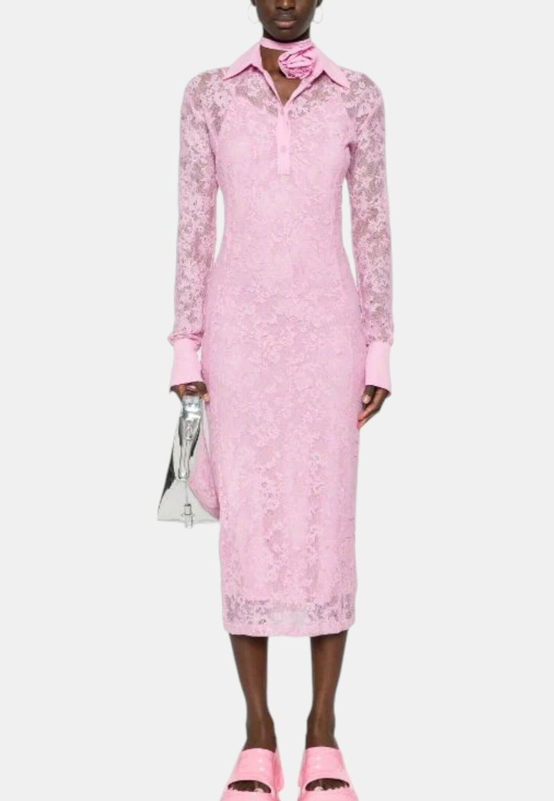 Abito in pizzo rosa con maniche lunghe e colletto, caratterizzato da una texture floreale. Abbinato a una borsa argentata e calzature rosa.