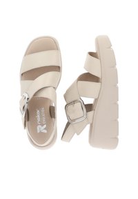 Sandales beige à bouts ouverts avec semelles épaisses, larges brides et boucles argentées, conçues pour un usage décontracté.