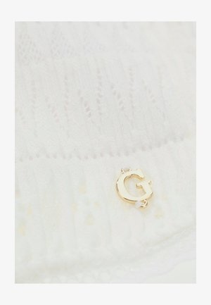 Weißes Strickgewebe mit einem kleinen goldfarbenen Metallbuchstaben "G", der nahe dem unteren Rand befestigt ist.