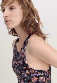 Floral-patterned sleeveless top featuring a black base with orange, purple, and pink accents. Smooth fabric with a fitted design.