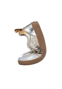 Scarpa metallica argento e oro, con tomaia texturizzata, suola in gomma marrone, chiusura con lacci e un motivo distintivo sul lato.