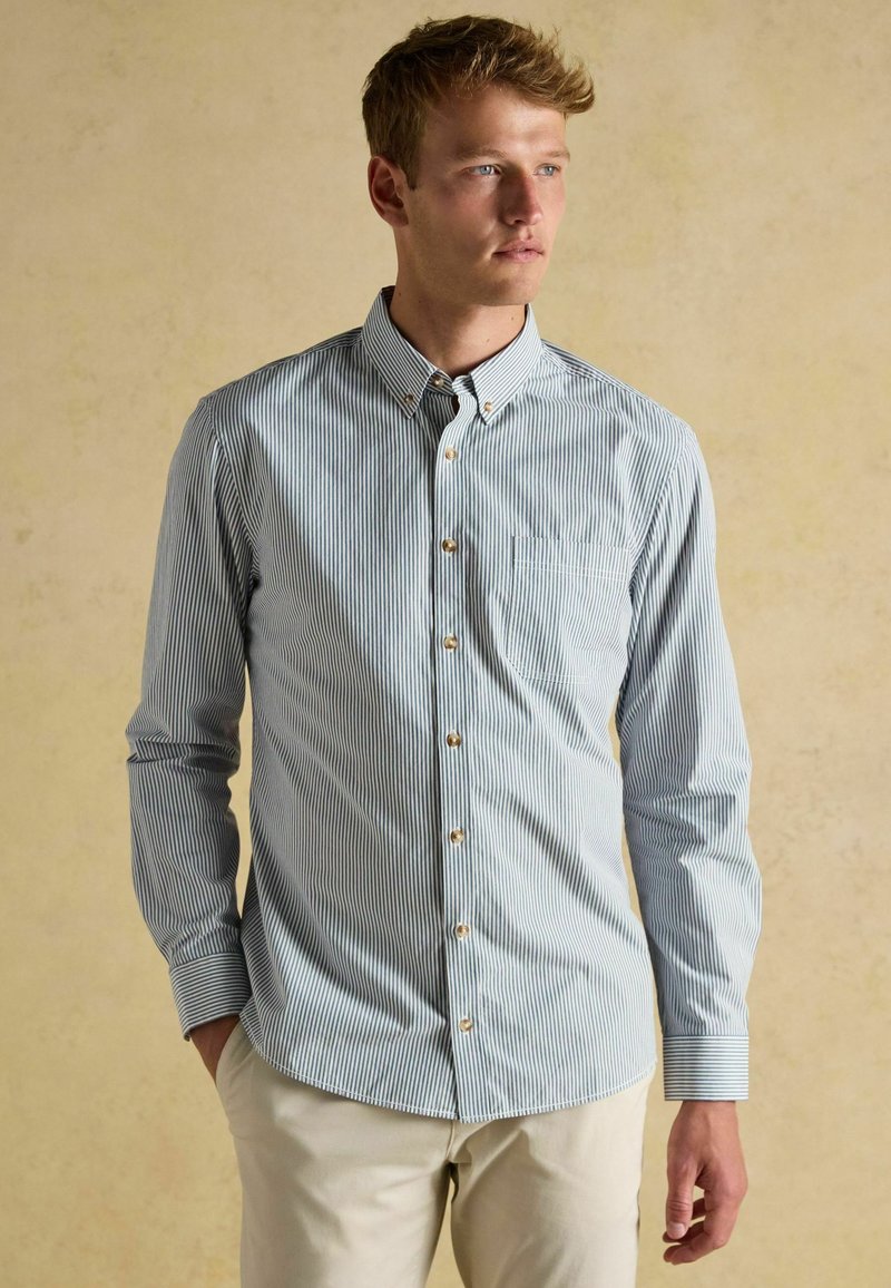 Koszula zapinana na guziki w jasnoniebieskie i białe pionowe paski, wykonana z bawełny, z długimi rękawami, kołnierzykiem zapinanym na guziki oraz kieszonką na piersi.