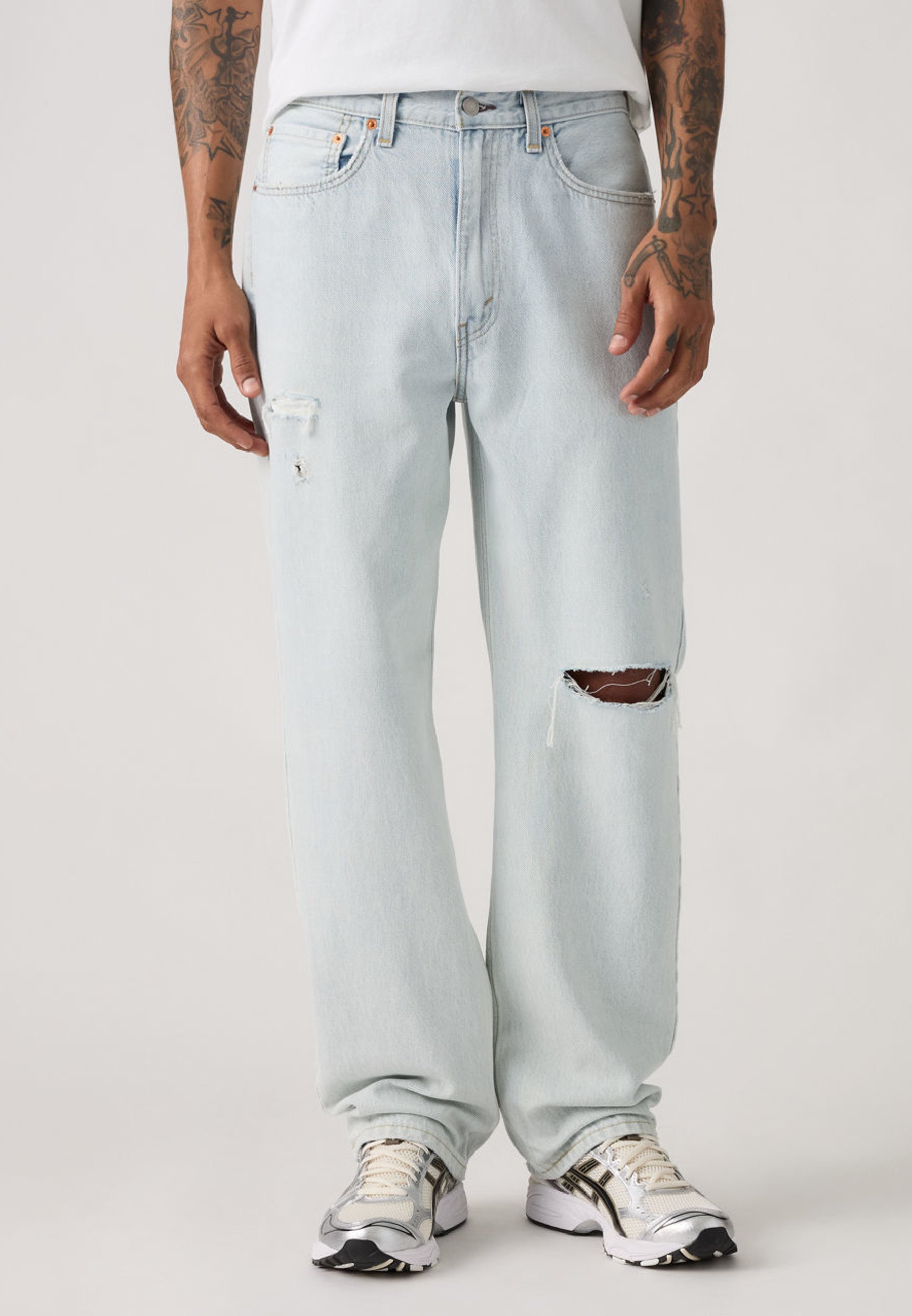 Light wash loose straight jeans with a single ripped knee