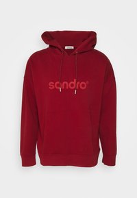 Czerwony sweatshirt z kapturem wykonany z miękkiego materiału, z kieszenią kangurzą i wyraźnym logo "sandro" w nieco jaśniejszym odcieniu.
