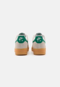 Tênis Nike Air com parte superior em camurça cinza, aba do calcanhar verde e sola de borracha natural. Design arredondado com colarinho e língua acolchoados.