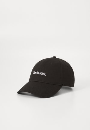 Schwarze Baseballkappe mit weiß gesticktem "Calvin Klein" Logo vorne, auf einer schlichten weißen Fläche präsentiert.