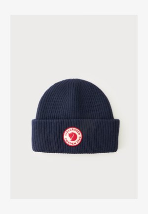 Bonnet en tricot côtelé bleu marine avec un revers plié comportant un patch rond rouge et blanc avec le logo Fjällräven Sweden 1960.