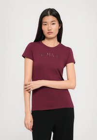 Burgunderfarbene kurzärmelige, taillierte T-Shirt mit Rundhalsausschnitt und geprägtem Logo auf der Vorderseite. Glattes Baumwollmaterial, kombiniert mit schwarzen Unterteilen.