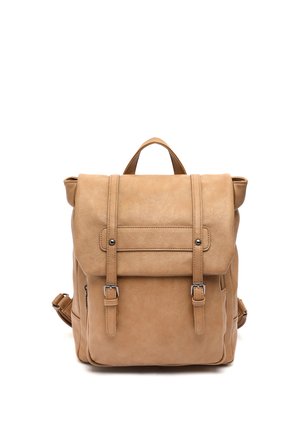 Vaaleanruskea nahkainen reppu, jossa etutaskun läppä kiinni kahdella solkiremminauhalla ja yläkahva, valkoisella taustalla kuvattuna.
