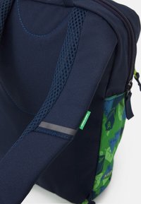 Marine rugzak met een gestructureerde afwerking, mesh schouderbanden, kleurrijke patronen en een klein groen label met de tekst "Green Share".