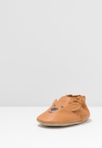 Brune lær baby sko med bjørnefacedesign, buet tå, blødt sål, elastisk ankel og Velcro-lukning. Simpelt og legende udseende.