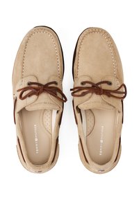 Beige suede boat shoes with brown leather laces, contrasting white stitching, and a smooth interior featuring perforations for breathability.
