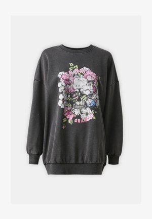Sweatshirt gris avec des manches longues et bouffantes ; présente un graphique de crâne floral en blanc, rose et bleu avec le texte "NE PRENEZ RIEN POUR ACCORDÉ."