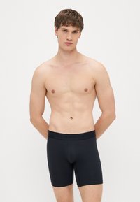 Fekete pamut boxeralsó rugalmas derékpánttal, amelyen a "Hollister" márkanév fekete betűkkel van nyomtatva. Sima, testhezálló kialakítás.