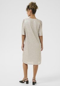 Satin-artiger, hellgoldener Kleid mit schimmernden Pailletten, kurzen Puffärmel und knielangem Schnitt, mit einem runden Rückenausschnitt.