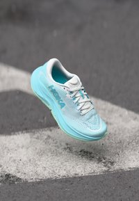 Light blue running shoe with a mesh upper, white accents, cushioned sole, and HOKA branding. The design features a streamlined shape and textured surface.