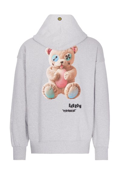 Felpa oversize grigia con una grande grafica di un orso sulla schiena, occhi blu a bottone, pancia rosa e scritte nere sottostanti.