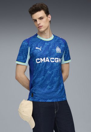 Blå sportsjersey lavet af åndbart stof med et struktureret grafisk mønster, der har korte ærmer, lyseblå accenter og et logo.