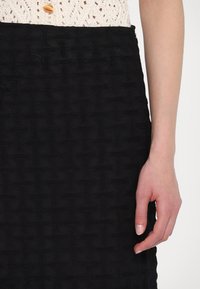 Mustmustekstuuriga seelik, millel on kootud muster. kangas on pehme ja kerge venivusega, millel on sobiv talje ja diskreetne detailitus.