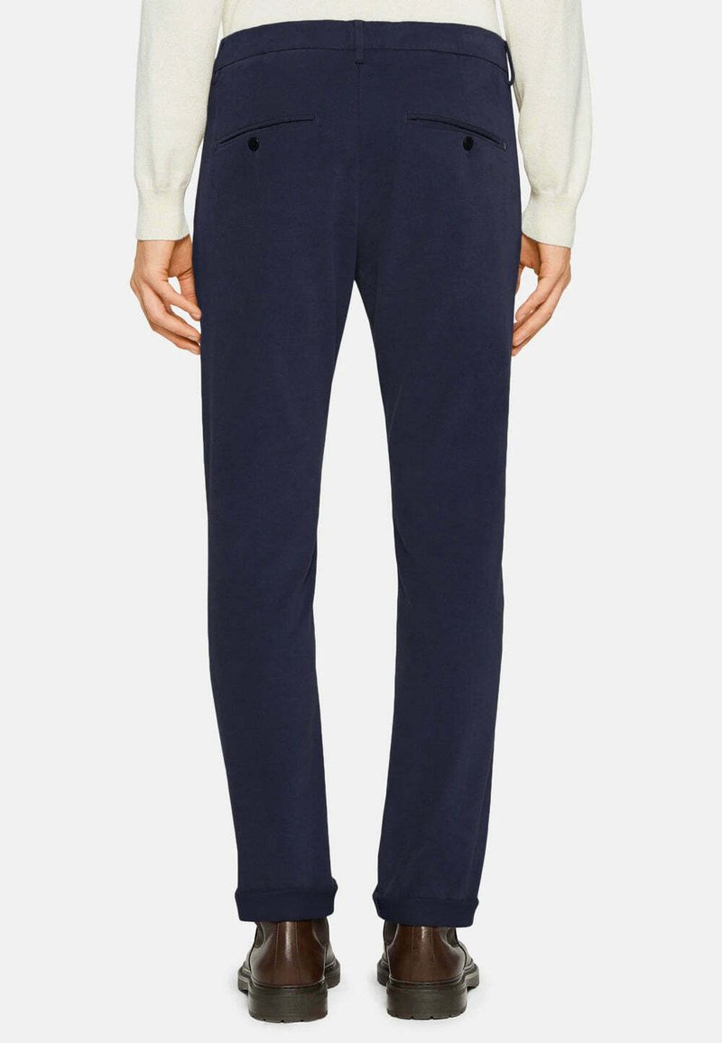 Pantalon marine à coupe ajustée, avec poches arrière à boutons, ourlets à revers et une texture de tissu lisse.