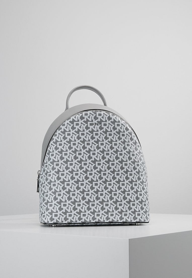 Grå och vit tygryggsäck med en böjd form, med ett geometriskt mönster, handtag på toppen och en dragkedjestängning på sidan.