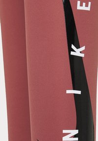 Leggings de sport rouges avec un design ajusté et élégant. Présente une bande noire brillante et du texte blanc sur le côté. Texture lisse, matériau extensible.
