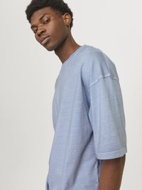 Lyseblå oversized t-shirt med korte �ærmer, rund halsudskæring og en blød tekstur. Har subtile syninger langs sømmene.