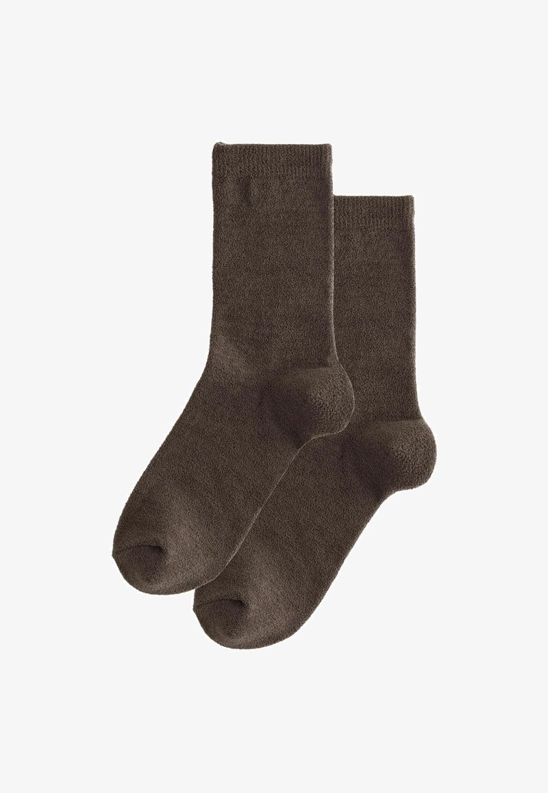 Chaussettes marron foncé en tissu doux et texturé, de longueur mi-mollet et avec un orteil renforcé. Design simple, sans motifs ni accents.
