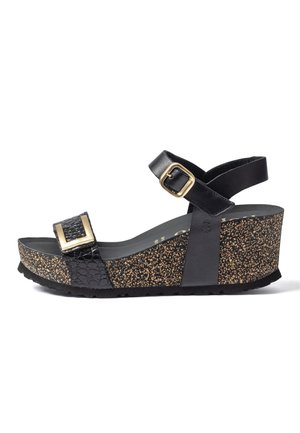 Sandalia de cuña negra con suela de patrón de corcho, hebilla dorada en la correa delantera y correa para el tobillo con hebilla dorada ajustable.