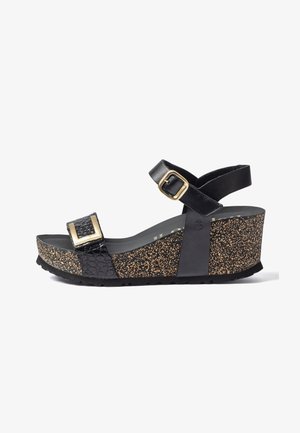 Sandalia de cuña negra con suela de patrón de corcho, hebilla dorada en la correa delantera y correa para el tobillo con hebilla dorada ajustable.