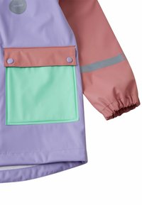 Έγχρωμο αδιάβροχο μπουφάν με σώμα σε λιλά, ροζ μανίκια, πράσινη μπροστινή τσέπη, ελαστικές μανσέτες και ανακλαστικές λεπτομέρειες στο μανίκι.