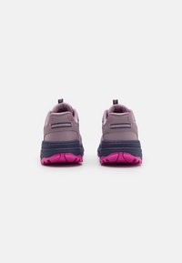 Des chaussures de sport violettes avec une tige texturée, des accents bleu marine foncé, une semelle rembourrée rose et des languettes renforcées au niveau du talon pour un enfilage facile.