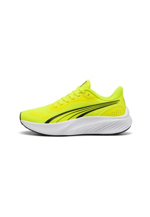 Zapatillas deportivas amarillas con parte superior de malla, acentos negros y una entresuela blanca con un patrón de agarre texturizado.