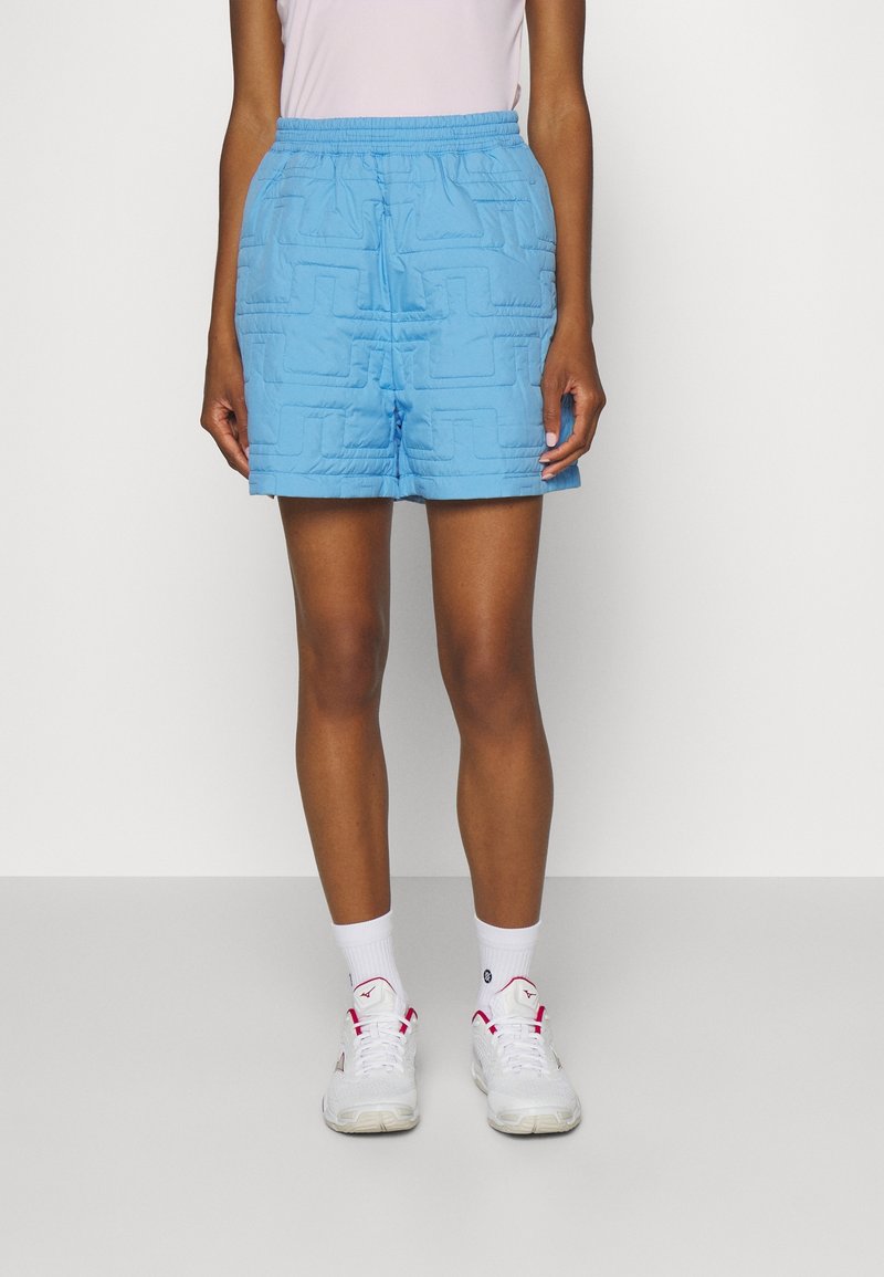 Light blue quilted shorts with an elastic waistband, featuring a textured geometric pattern and a relaxed fit. Accented with white sneakers.