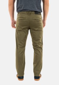 Pantalones verde oliva de corte ajustado, confeccionados en una mezcla de algodón. Cuentan con dos bolsillos traseros, pasadores para cinturón y una textura suave.