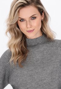 Grå ribbede turtleneck sweater med en let løs pasform, præget af et tekstureret stof og en høj halsudskæring.