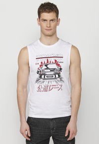 Bijela majica bez rukava s grafikom trkaćeg automobila i natpisom "TOKYO" te japanskim tekstom u crvenoj boji. Mekani pamučni materijal; ležeran dizajn.