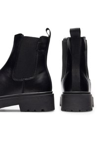 Čierne kožené členkové čižmy s elastickými bočnými panelmi, textúrovanou gumovou podrážkou a zadnými ťahacími pútkami. Jednoduchý, moderný dizajn bez ozdôb.