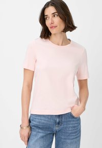 T-shirt rosa chiaro a maniche corte con collo rotondo, realizzato in tessuto morbido. Abbinato a jeans in denim blu, con una vestibilità comoda.