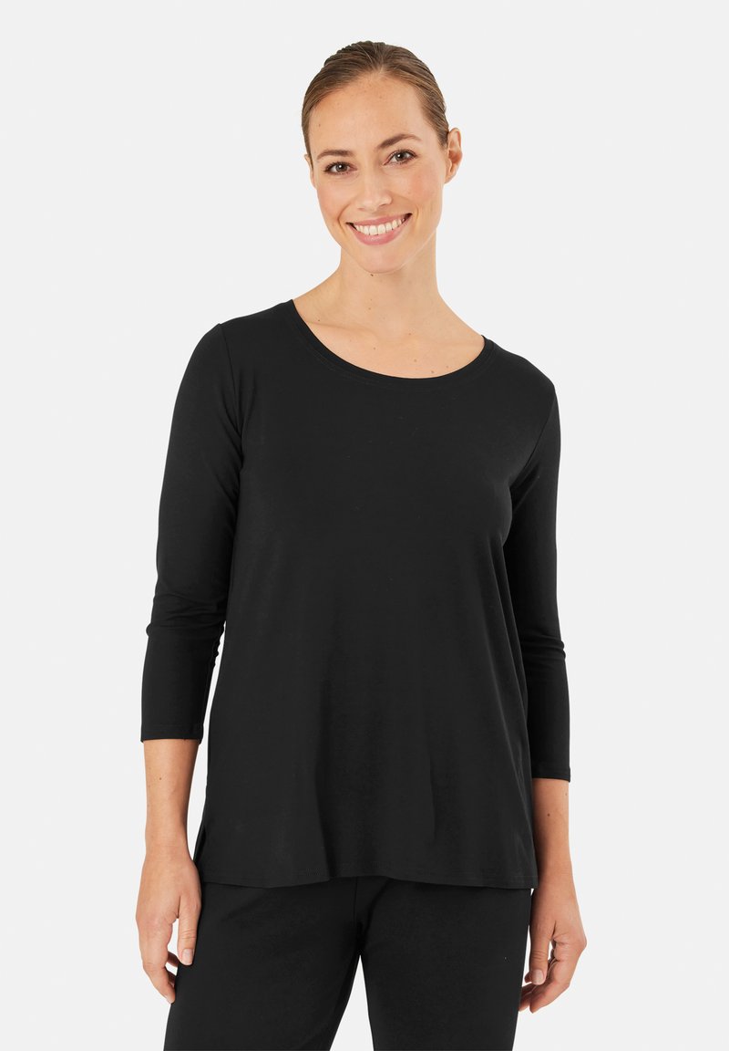 Czarny longsleeve z miękkiego materiału, z okrągłym dekoltem i luźnym krojem. Uzupełniony czarnymi spodniami, podkreślając minimalistyczny design.