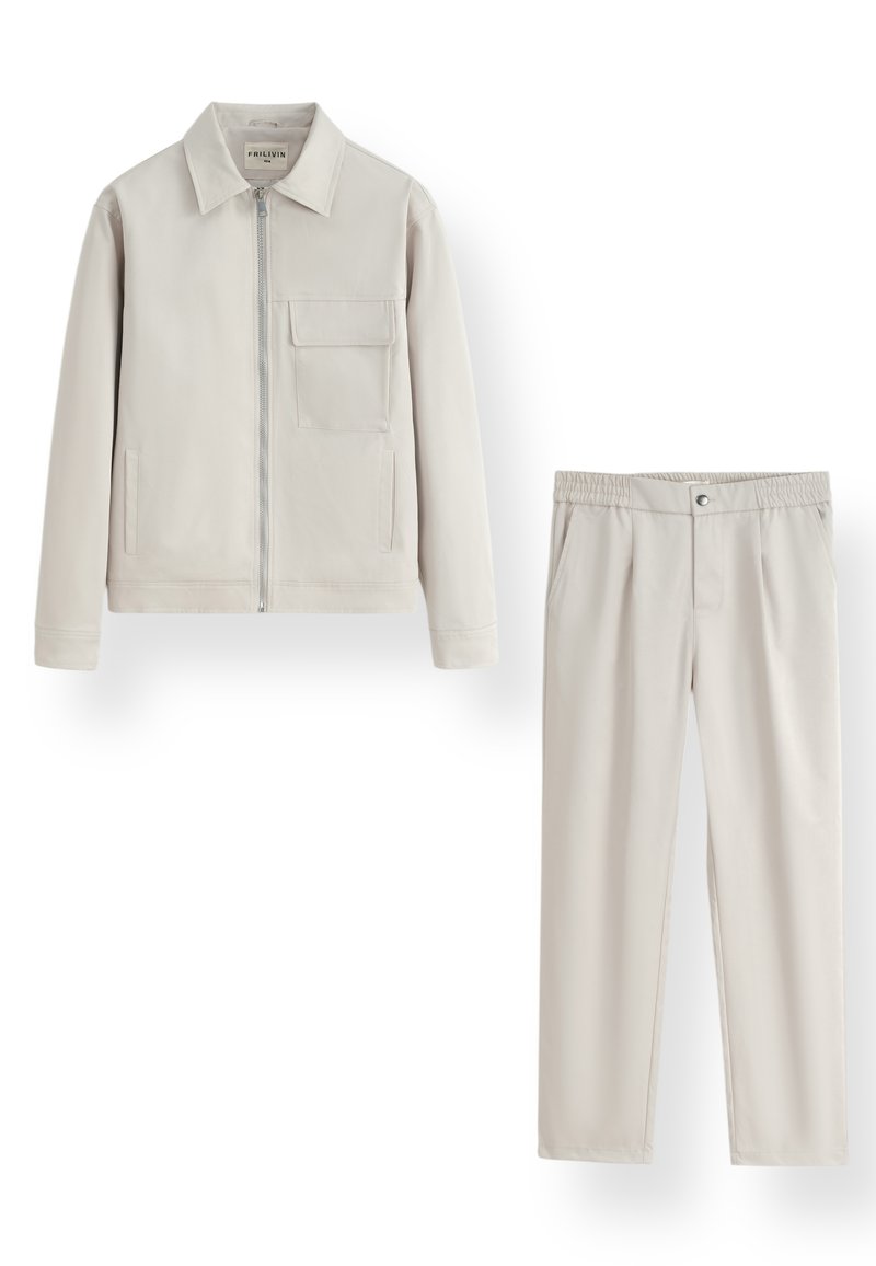 Veste zippée beige clair avec col et poche poitrine, assortie à un pantalon élastique à taille.