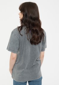 Gray oversized t-shirt with short sleeves, soft texture, faded color, and a relaxed fit, shown from the back against a white background.