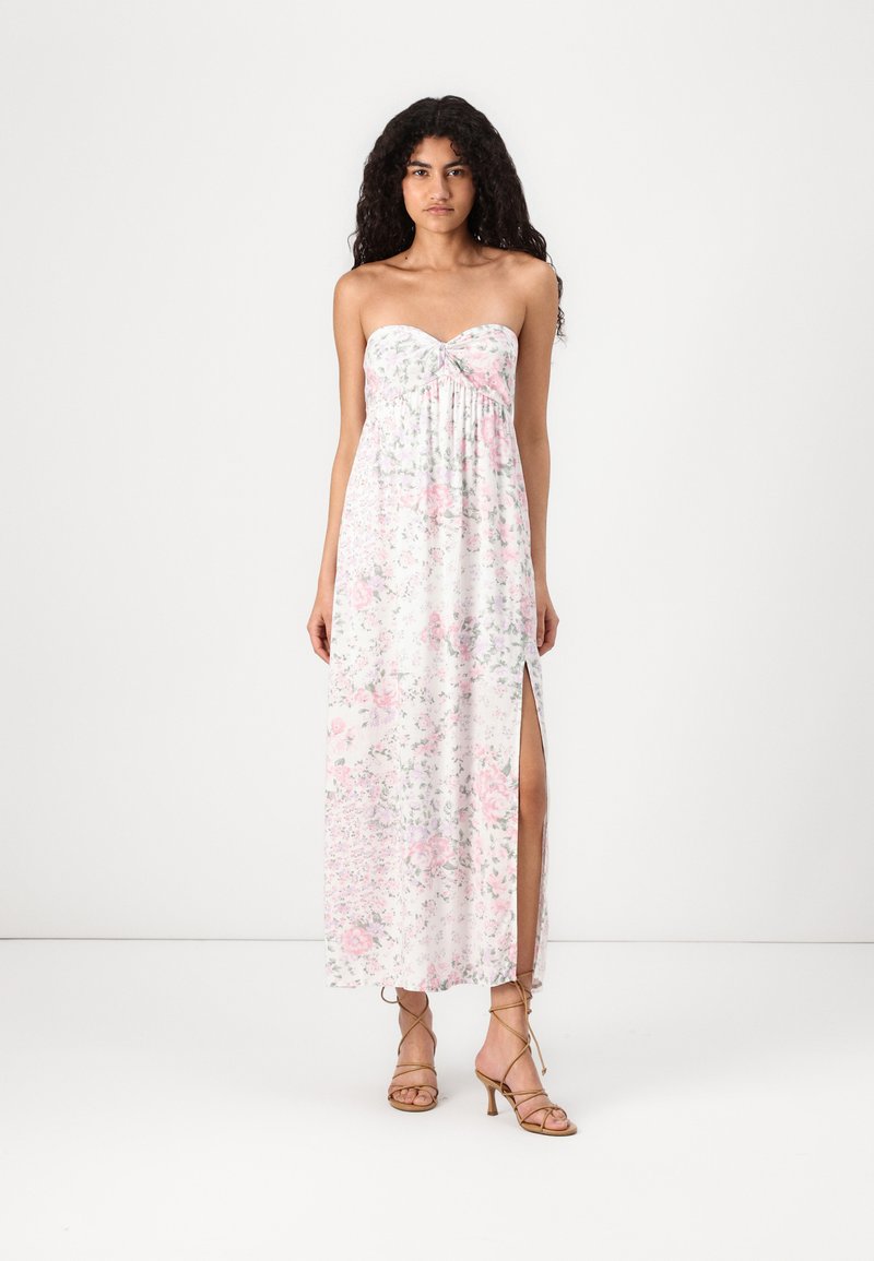 Robe maxi en tissu léger, présentant un design sans bretelles et un motif floral pastel ; fente sur le côté et détails froncés au niveau de la poitrine.